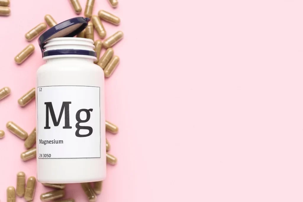 Mg pills with a plastic bottle with a light pink background. 