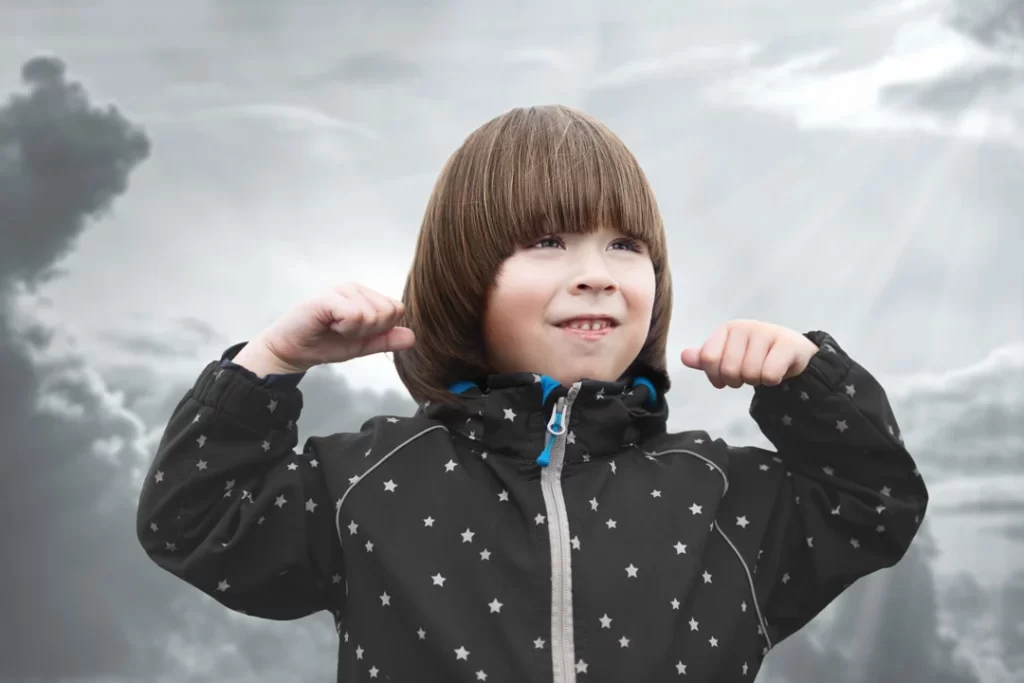 small boy is showing power sign on sky background