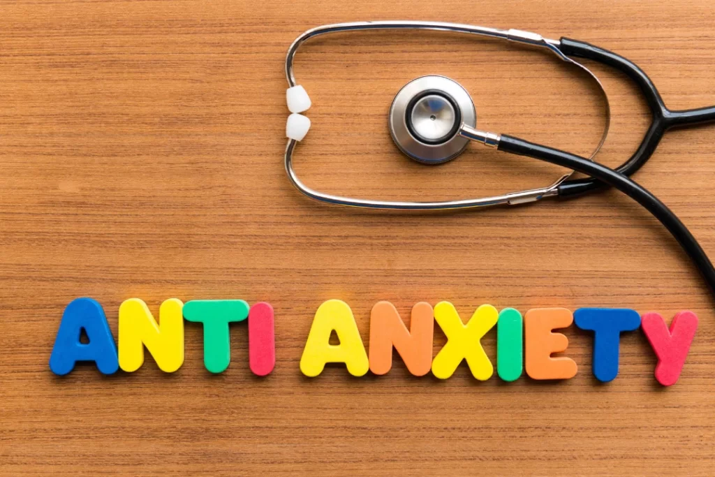 Anti Anxiety is written with plastic alphabet blocks and a stethoscope on a wooden table. 