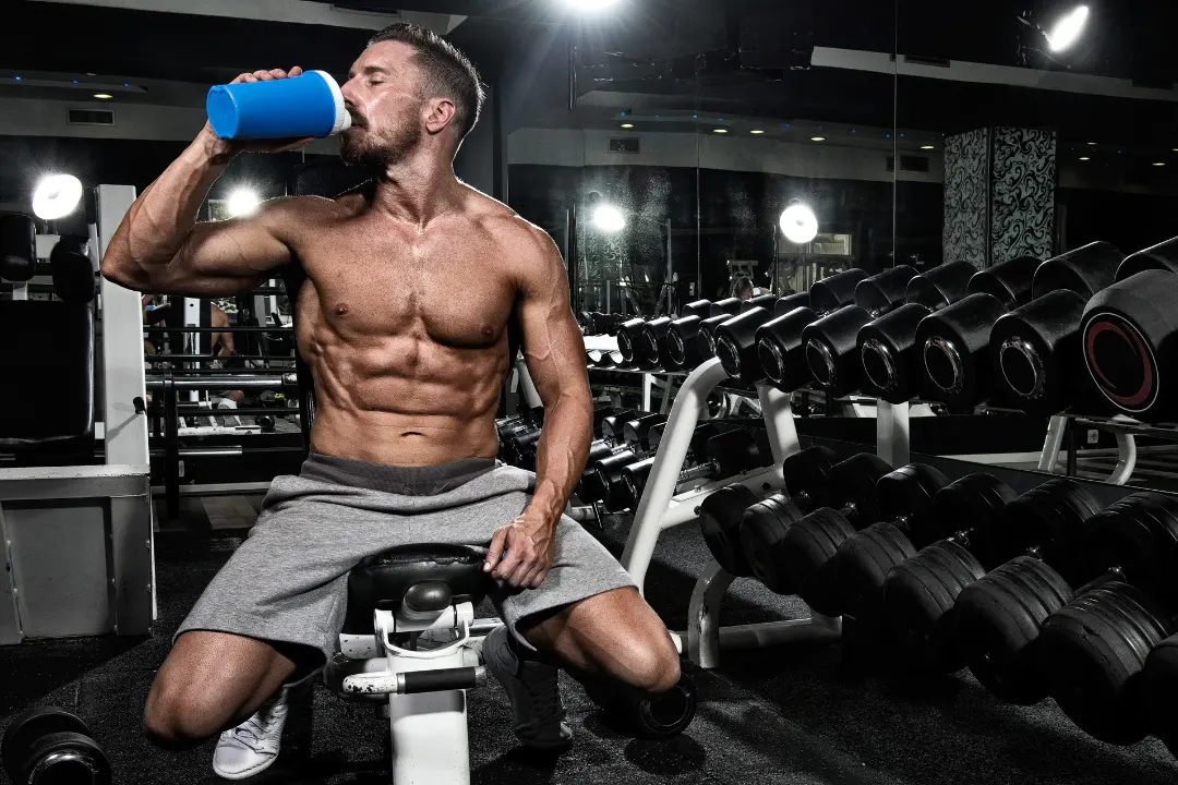 Athlete drinking energy drink while sitting in the gym.