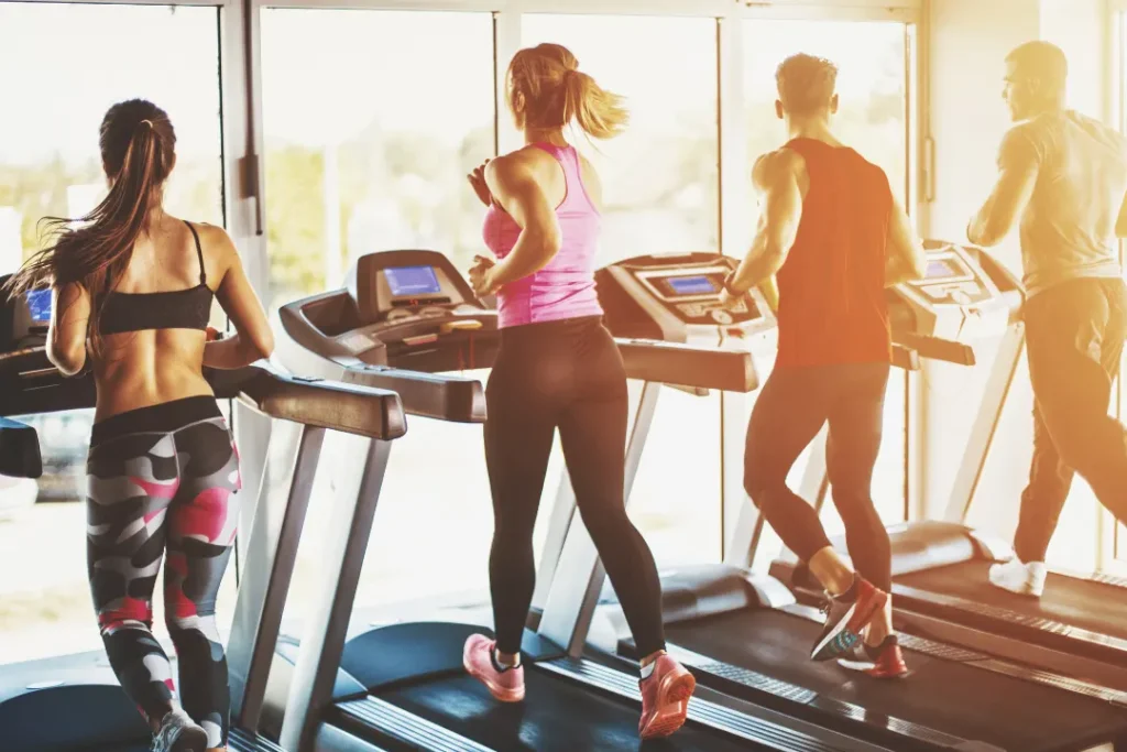 People do jogging in the gym on the treadmill.