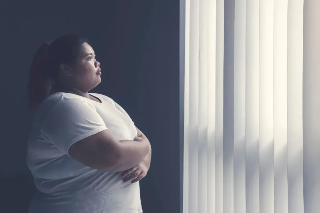 An over weight lady standing near window. 